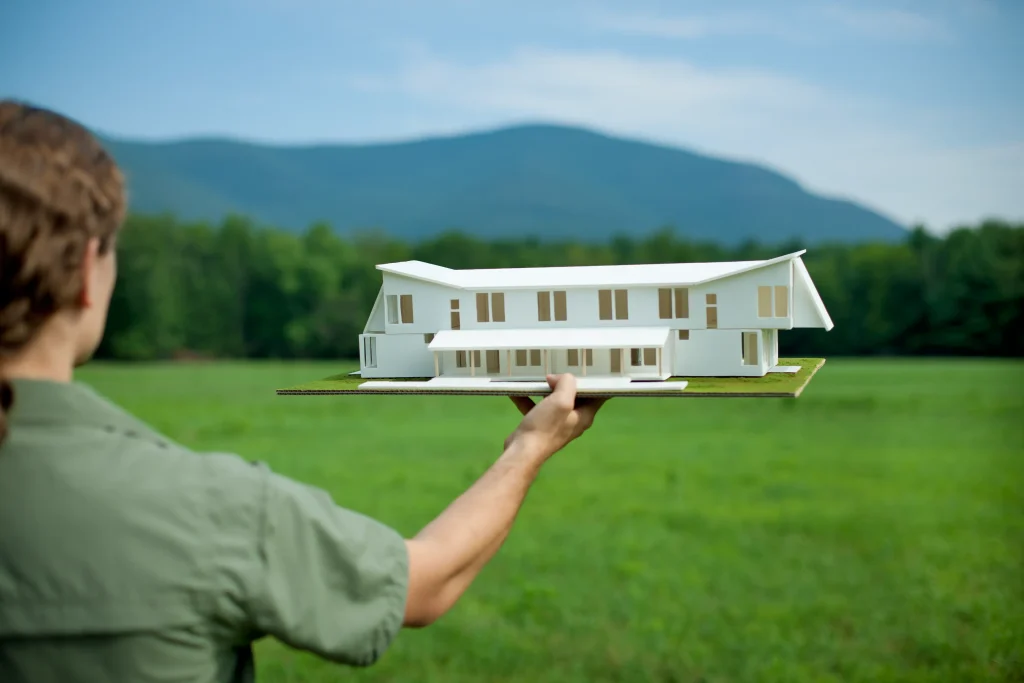 Planning the ideal location for custom homes with model house and open landscape background.